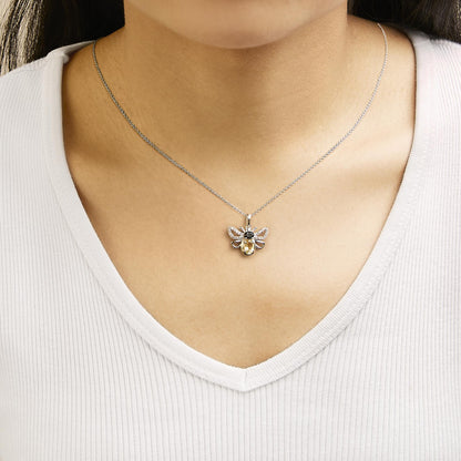White metal necklace shown worn on a model, featuring a bee-shaped pendant with an oval orange gemstone, an oval black gemstone, and multiple round white gemstones, photographed from the front.