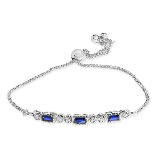 White metal bracelet with alternating blue baguette-shaped gemstones and white round gemstones, shown in a top-down view.