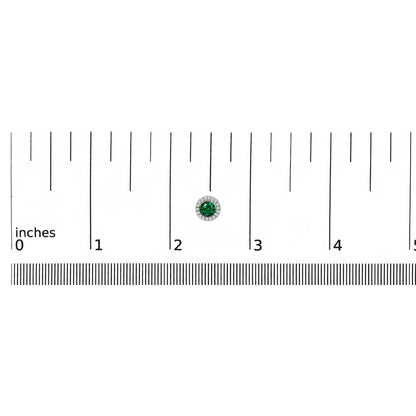 White metal round earring with a green round gemstone center surrounded by small white round gemstones, shown on a ruler scale from a front angle.
