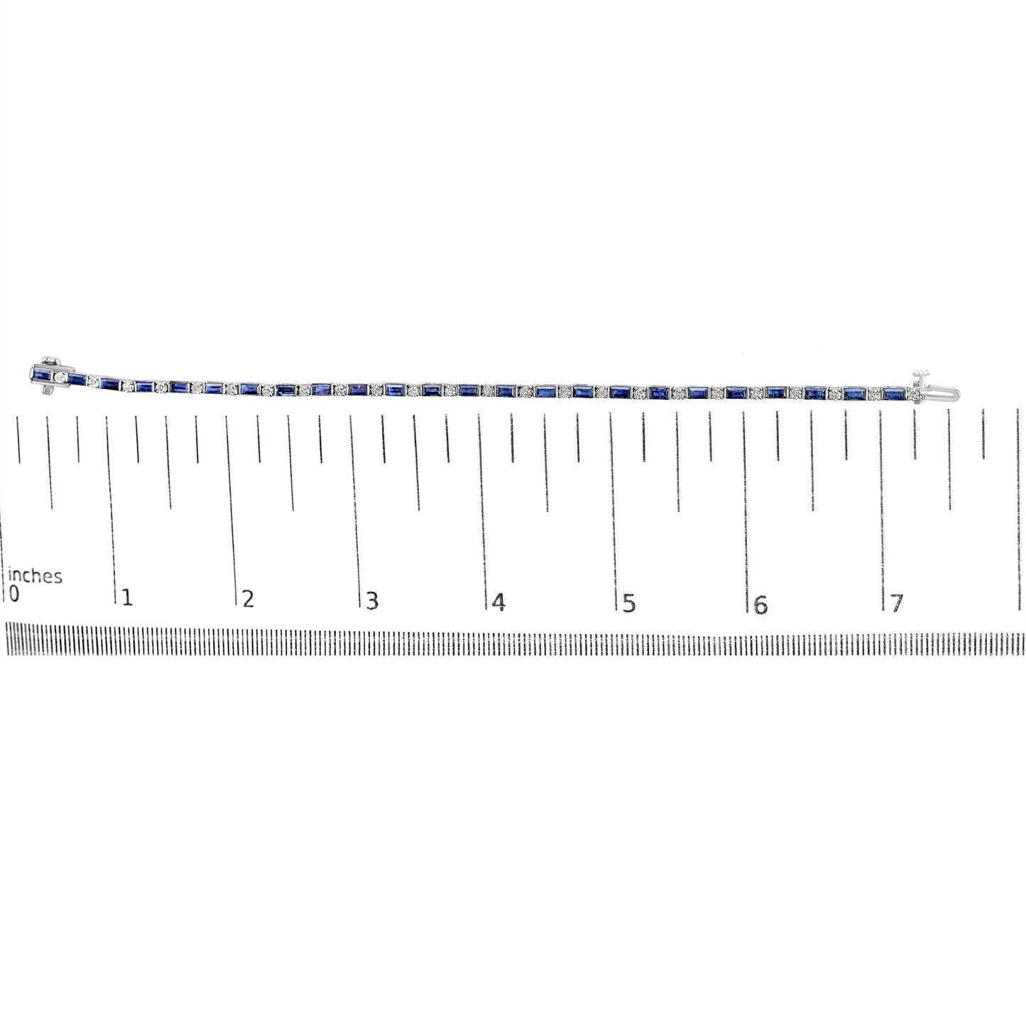White metal bracelet with alternating blue baguette-shaped gemstones in channel settings and round white gemstones in prong settings, displayed flat on a ruler for size reference, top-down view.
