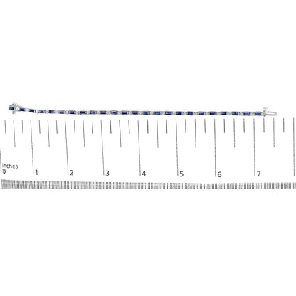 White metal bracelet with alternating blue baguette-shaped gemstones in channel settings and round white gemstones in prong settings, displayed flat on a ruler for size reference, top-down view.