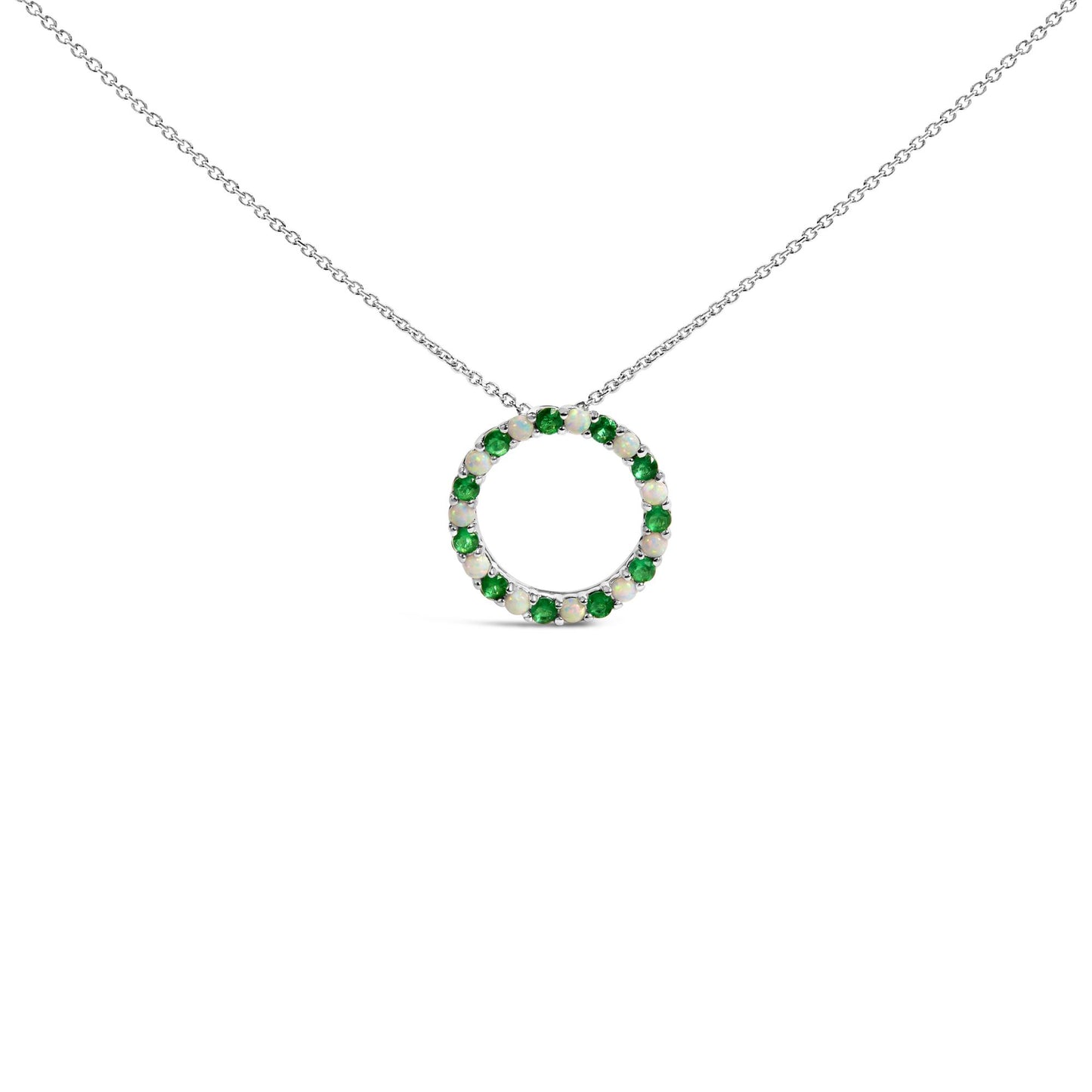 Front-facing shot of a white metal circular necklace pendant adorned with alternating round green and white gemstones in a shared prong setting.