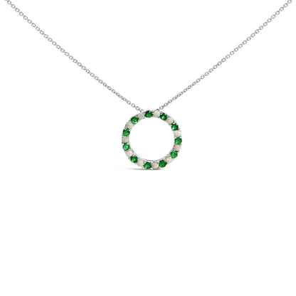 Front-facing shot of a white metal circular necklace pendant adorned with alternating round green and white gemstones in a shared prong setting.