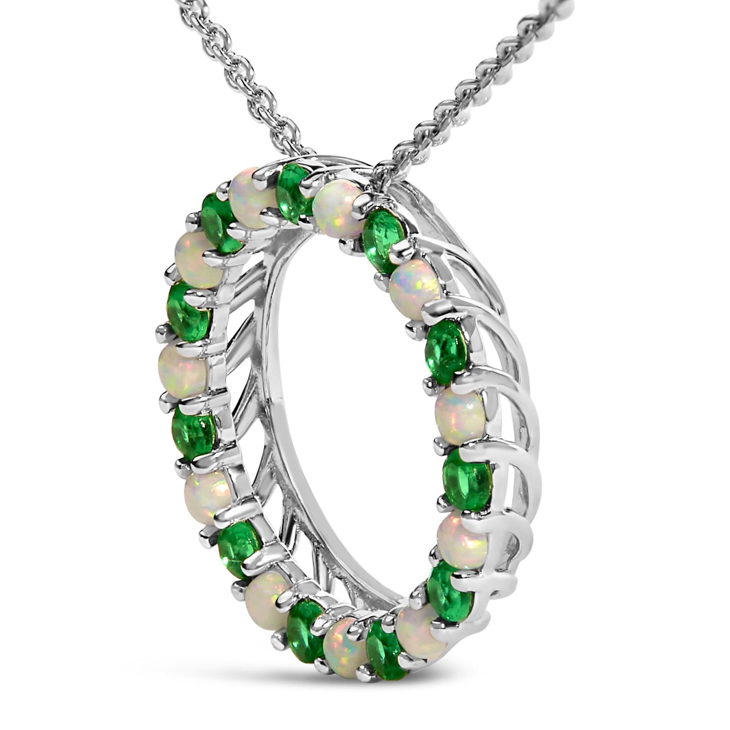 Close-up front angle of a white metal circular necklace pendant featuring alternating round green and white gemstones in shared prong settings, shown on a chain.