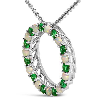 Close-up front angle of a white metal circular necklace pendant featuring alternating round green and white gemstones in shared prong settings, shown on a chain.