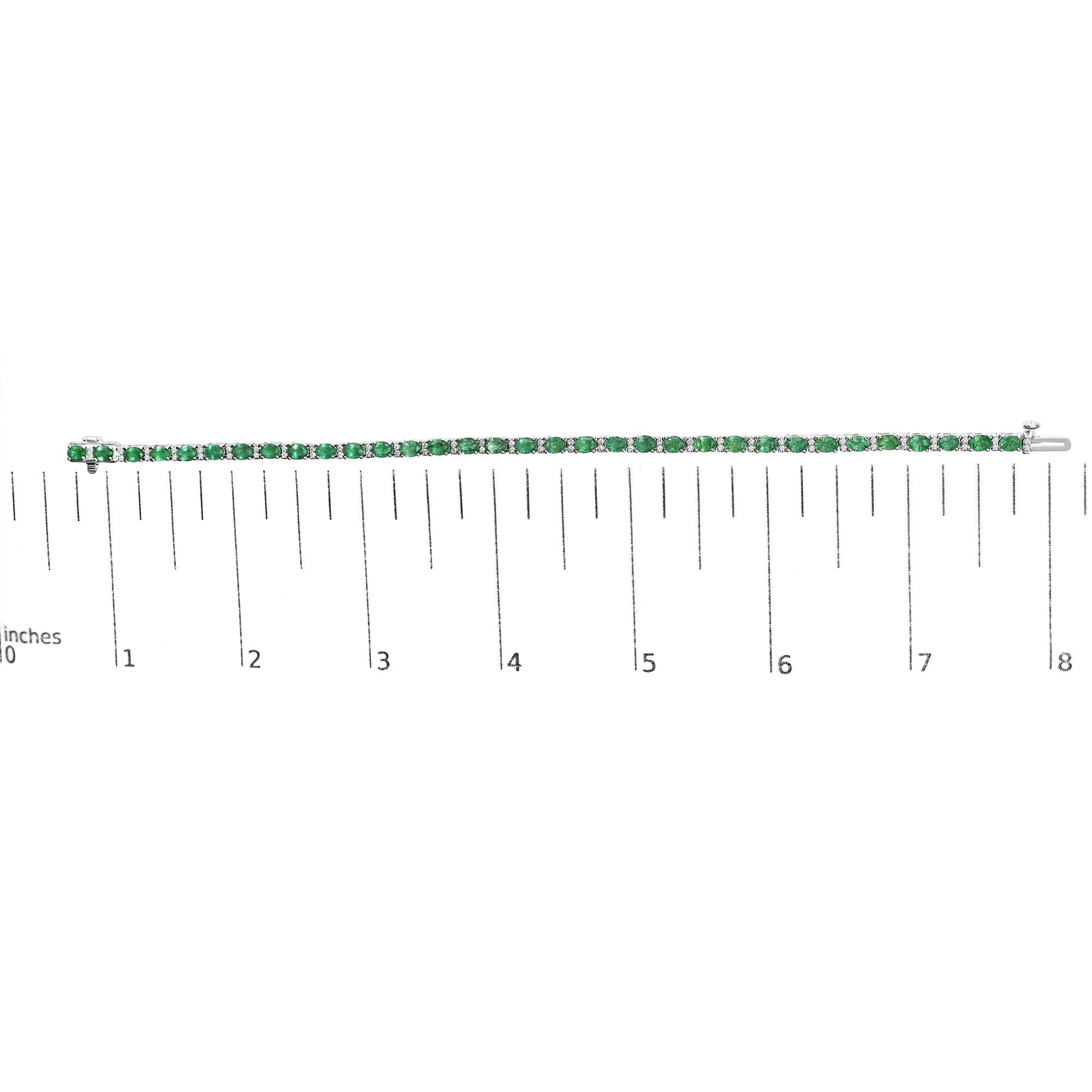 Bracelet with alternating round white gemstones and oval green gemstones set in white metal, shown lying flat on a ruler for scale, photographed from above.