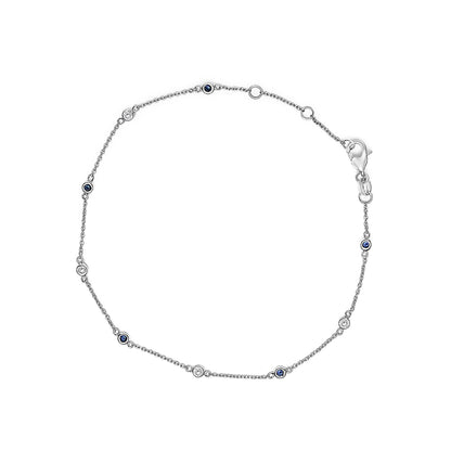 Top-down view of a white metal bracelet with alternating round bezel-set white and blue gemstones.