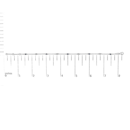 White metal bracelet with alternating round white and blue gemstones in bezel settings, laid flat on a ruler for size reference, front-facing angle.