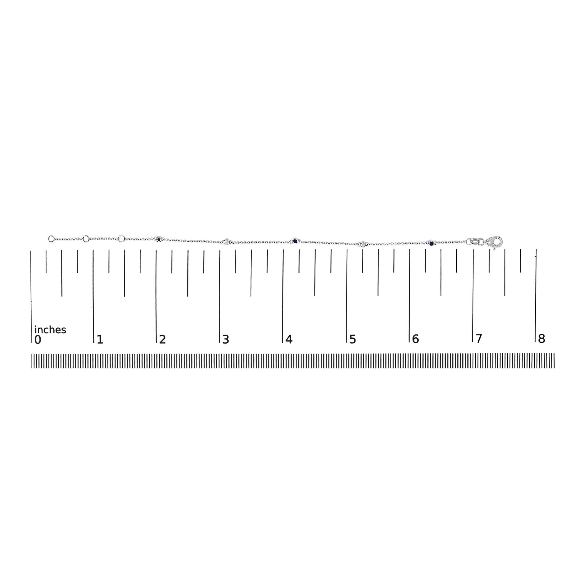 White metal bracelet with round white and blue gemstones in bezel settings, shown on a scale from a top-down angle.