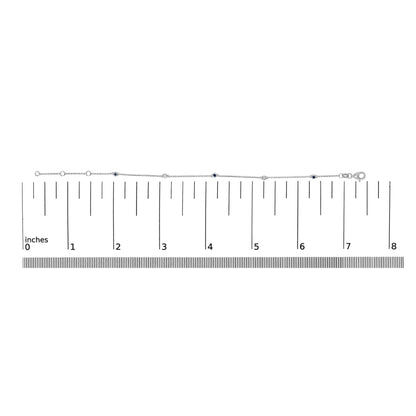 White metal bracelet with round white and blue gemstones in bezel settings, shown on a scale from a top-down angle.