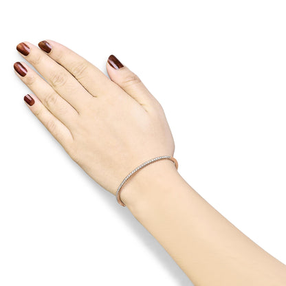 Rose metal bracelet with pave set white round gemstones, worn on a model's wrist, shot from an overhead angle.