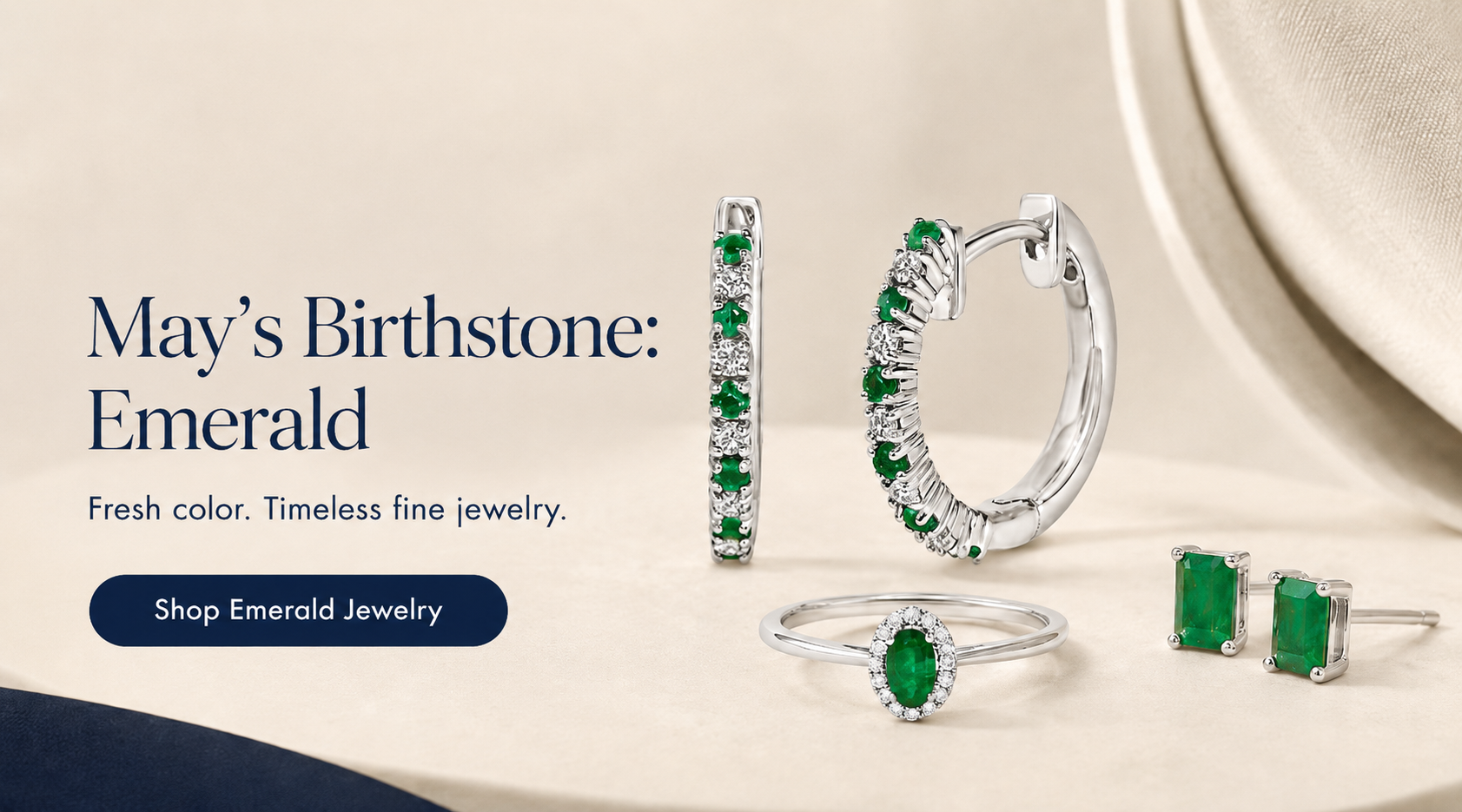 Emerald jewelry set including earrings and rings on a beige background with text about May's birthstone.