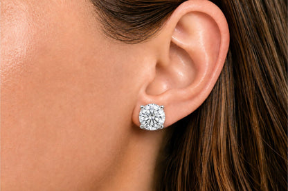 Close-up side view of a model wearing a white metal stud earring with a round white gemstone in a four-prong setting.