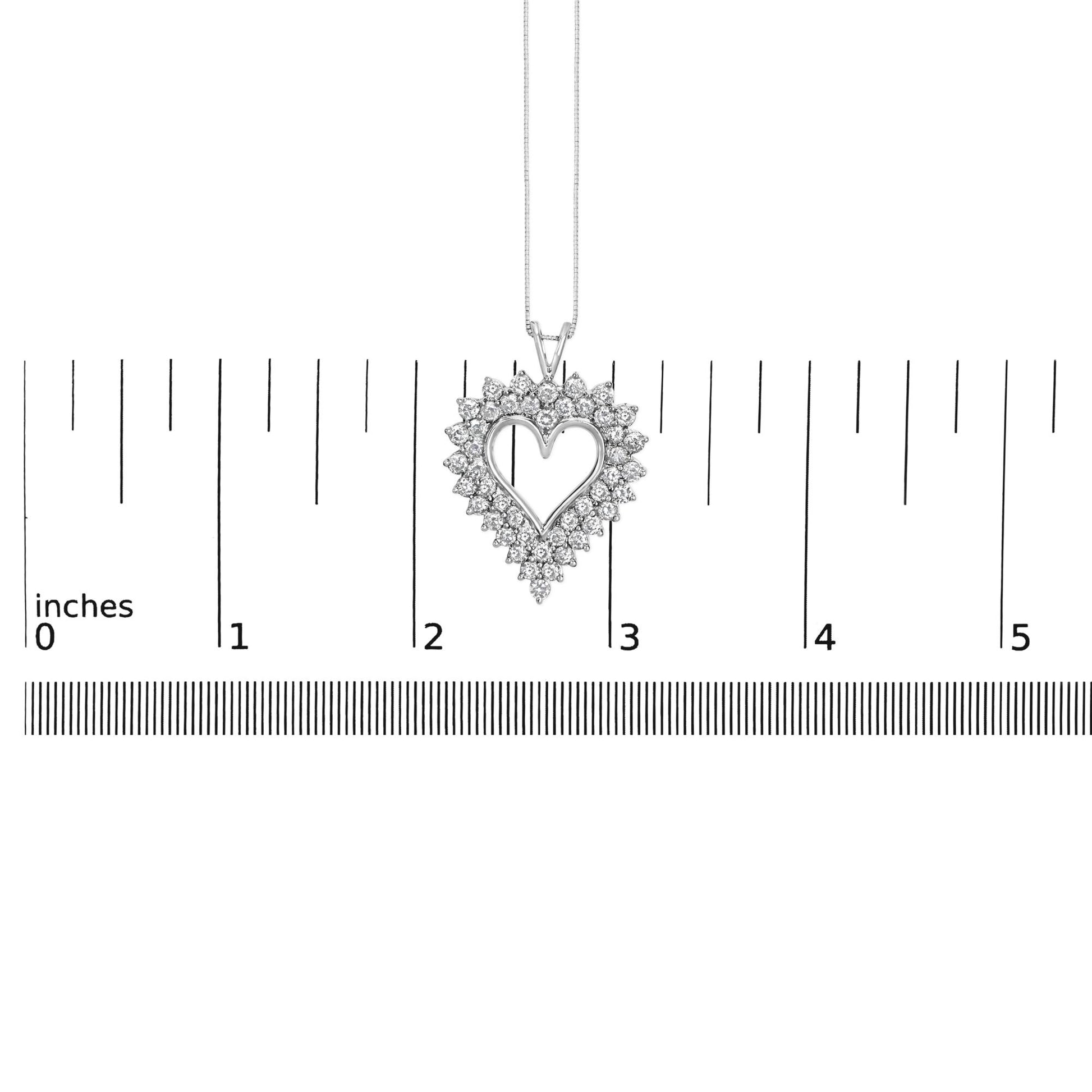Pendant necklace with a white metal heart-shaped frame surrounded by prong-set round brownish gemstones, shown hanging above a ruler for size reference, front view.