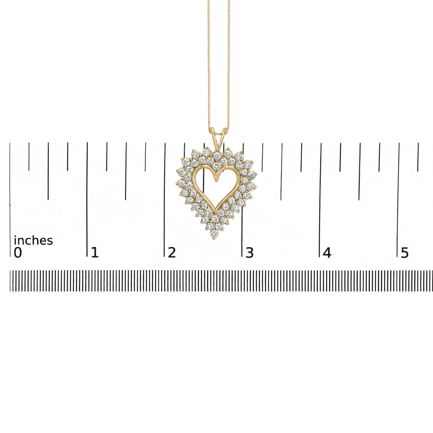 Yellow metal heart-shaped necklace pendant with prong-set round brownish gemstones, shown hanging centered over a ruler for size reference, front-facing angle.