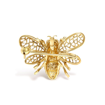 Close-up front angle of a yellow and white metal brooch shaped like a bee with openwork wings and round white gemstones on its body, shown on a white background.