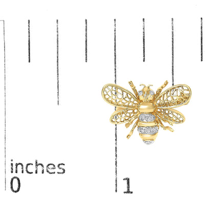 Close-up front view of a yellow and white metal bee-shaped brooch with white gemstones on the eyes and body, shown on a scale background.
