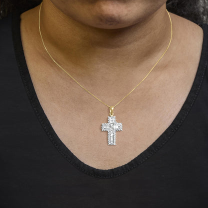 Close-up front view of a model wearing a yellow necklace with a cross-shaped pendant featuring white round prong-set gemstones surrounding white baguette channel-set gemstones.