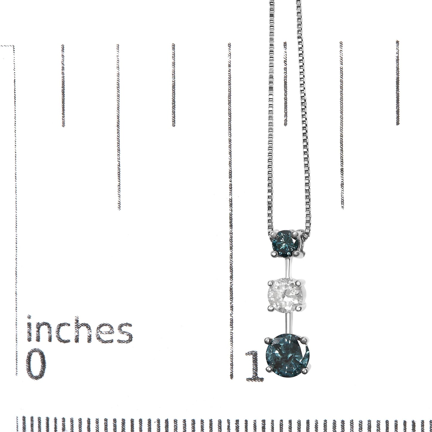 White metal necklace with three round prong-set gemstones, two blue and one white in the center, hanging vertically, photographed on a ruler for size reference.