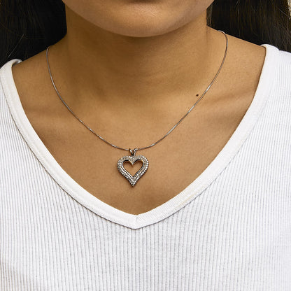 Close-up front view of a rose-colored heart-shaped necklace pendant with white round gemstones in prong settings, worn on a model.