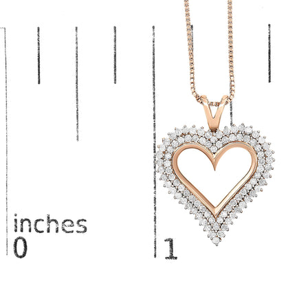 Close-up front view of a rose-colored heart-shaped necklace pendant with round white gemstones surrounding the outer edge, displayed on a ruler for size reference.