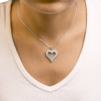 Close-up front view of a white metal necklace with a heart-shaped pendant adorned with small round white gemstones worn on a model.
