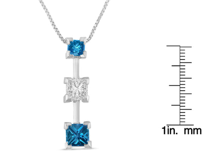 Front view of a white metal necklace pendant with three vertically aligned princess-shaped gemstones in prong settings, two blue and one white gemstone in the center, shown next to a ruler for size reference.