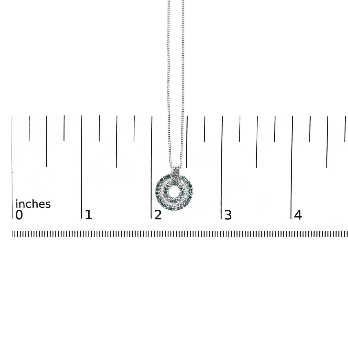 Close-up front view of a white metal necklace pendant with round blue gemstones in prong settings and white baguette gemstones in channel settings, shown on a scale.