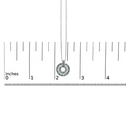 Close-up front view of a white metal necklace pendant with round blue gemstones in prong settings and white baguette gemstones in channel settings, shown on a scale.