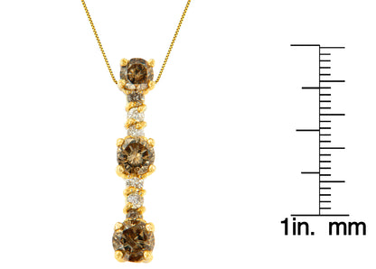 Front view of a yellow metal necklace with a vertical pendant featuring alternating round champagne and white gemstones in prong settings, shown next to a ruler for size reference.