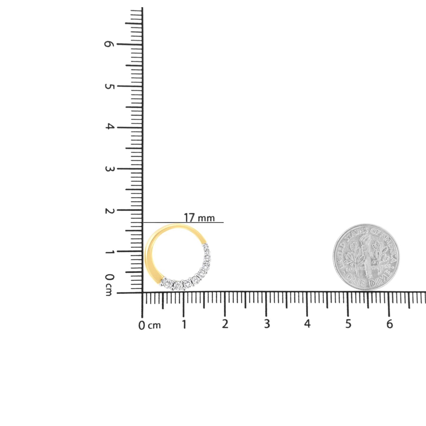 Top-down view of a yellow metal circular necklace pendant with white round gemstones in prong settings, placed on a ruler and scale for size reference.