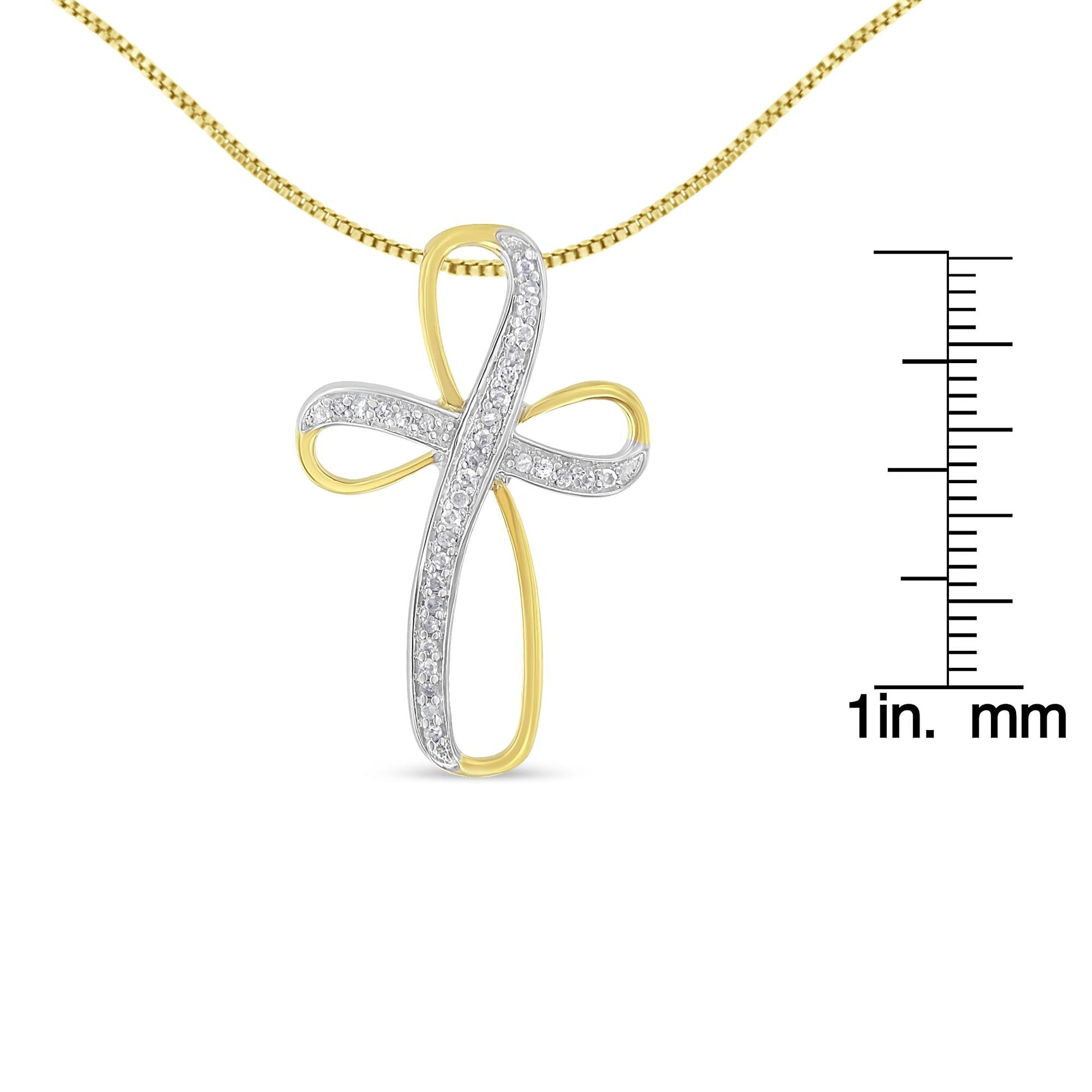 Front view of a yellow and white metal cross-shaped necklace pendant with white gemstones in a pave setting, displayed next to a ruler for size reference.