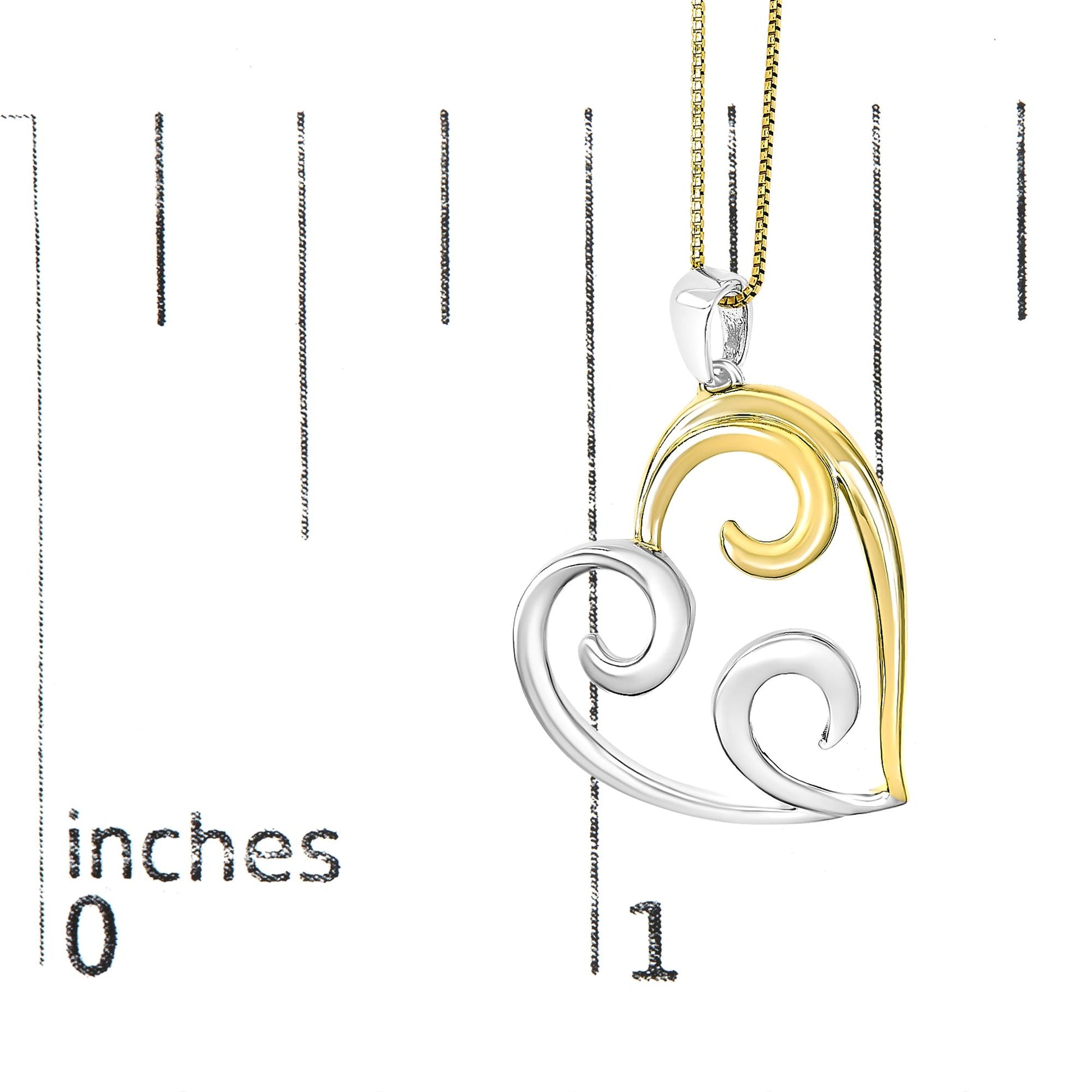 Two-toned metal heart-shaped necklace pendant with swirling design shown hanging next to a ruler for size reference, front angled view.