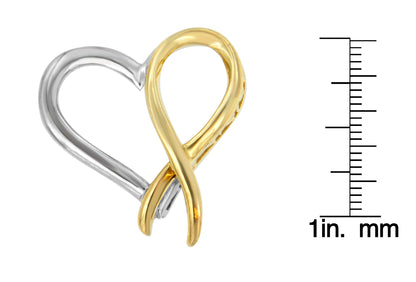 Close-up front angle of a two-toned necklace pendant shaped in an intertwined heart and ribbon design, placed next to a ruler for size reference.