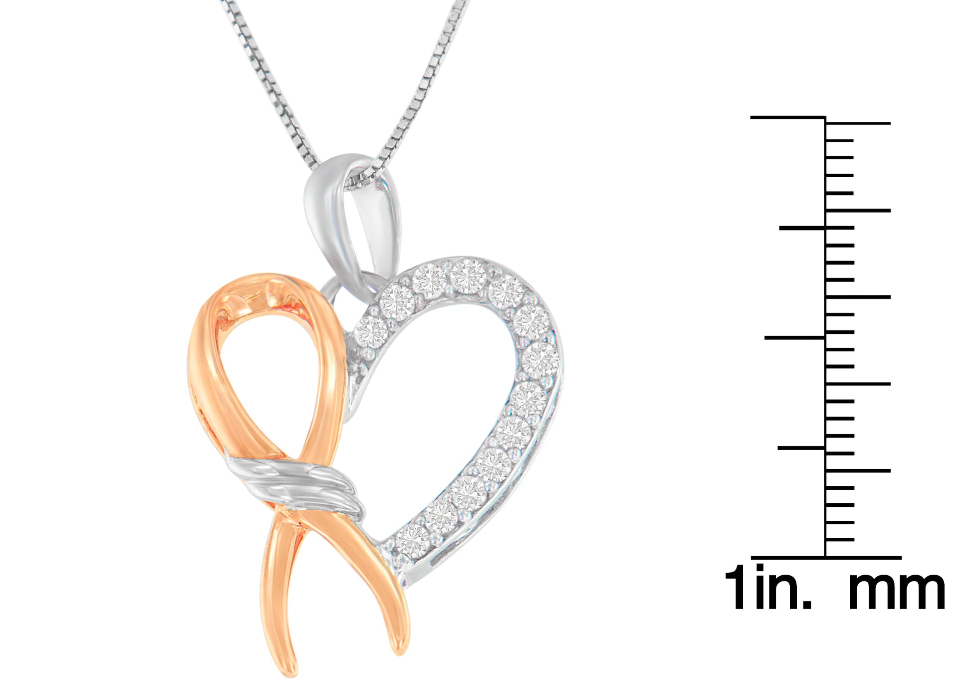 Two-toned necklace pendant in heart shape with one side featuring white gemstones in prong setting, shown in a close-up front angle, displayed next to a ruler for size reference.