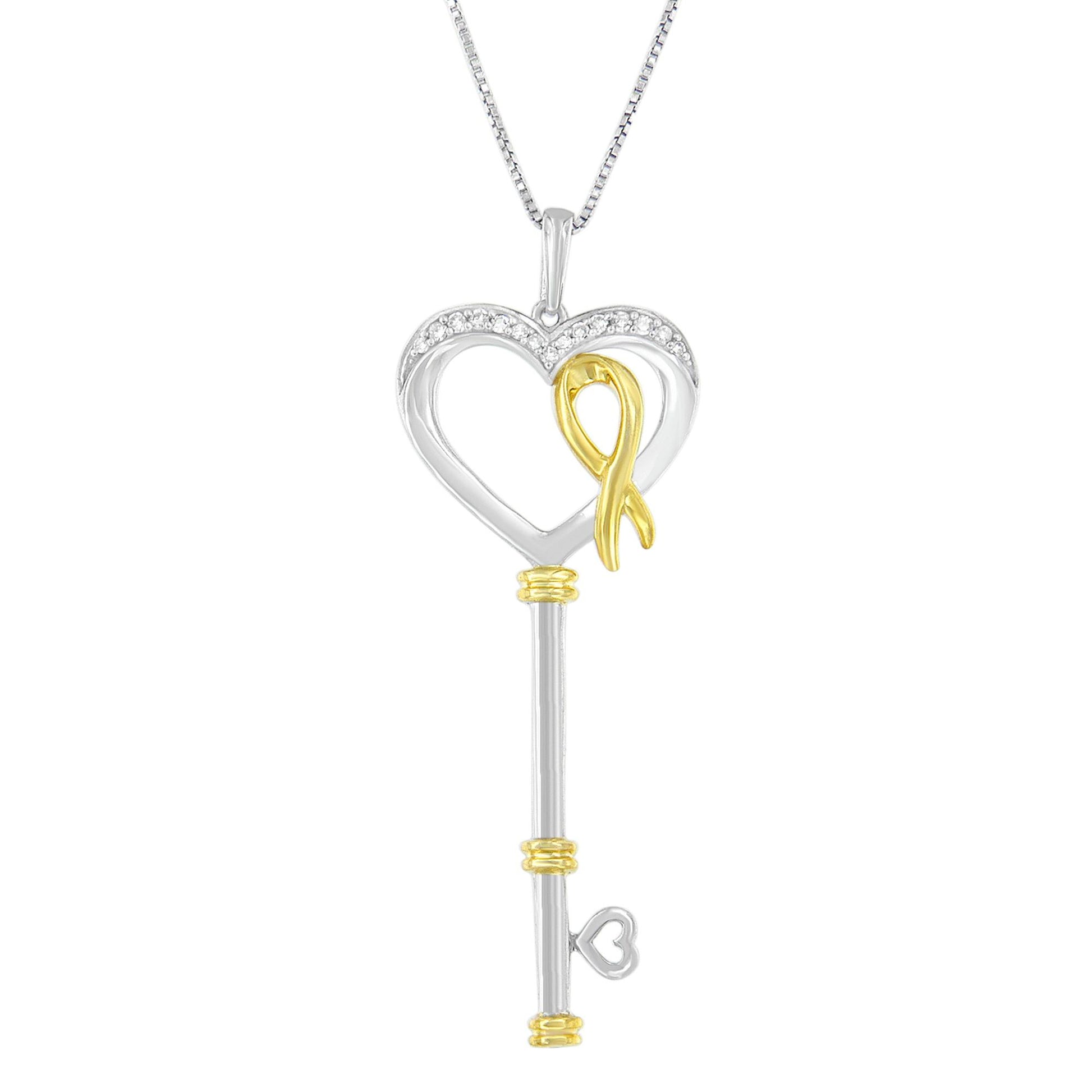 Front-facing image of a two-toned necklace pendant in the shape of a key with a heart-shaped top adorned with white round gemstones in prong settings and a gold ribbon detail.