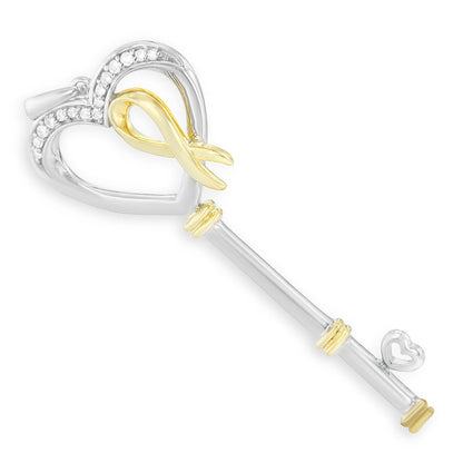 Two-toned key-shaped necklace pendant with heart-shaped top partially set with round white gemstones, shown in a top-down angle.