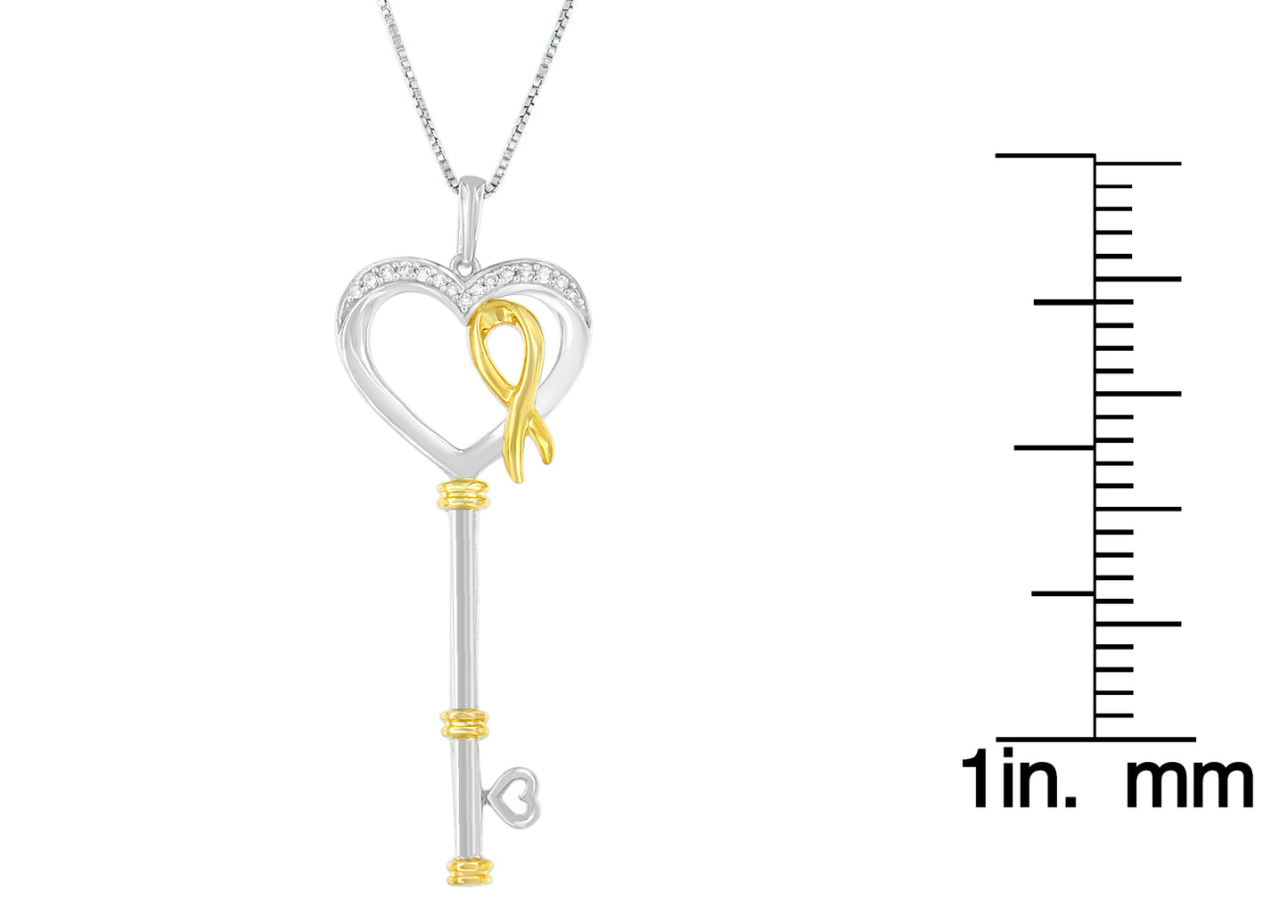 Front view of two-toned key-shaped necklace pendant with heart-shaped top, adorned with small white round prong-set gemstones and a gold-toned ribbon detail, shown next to a ruler for size reference.