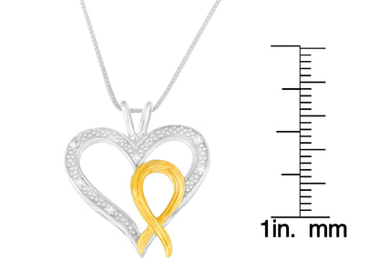 Two-toned heart-shaped necklace pendant with round white gemstones set in the silver part and a gold ribbon detail, shown front-facing next to a ruler for size reference.
