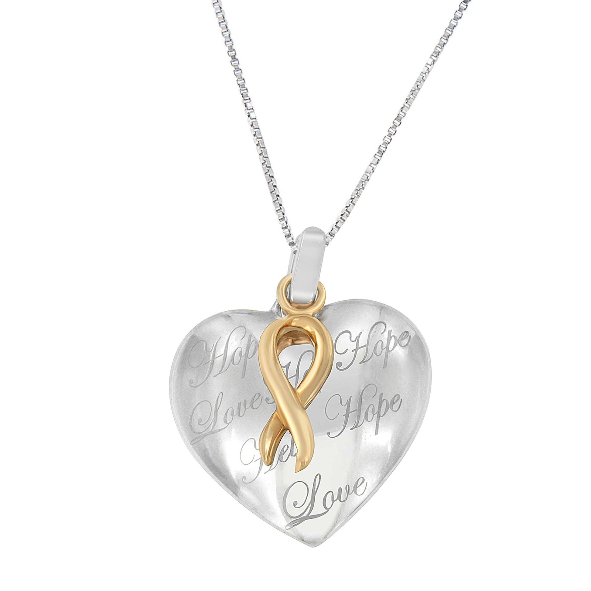 Front angle of a two-toned heart-shaped necklace pendant with engraved words and a gold-toned ribbon design on a silver-toned chain.