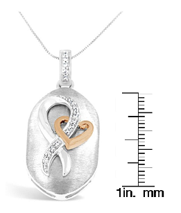 Two-toned necklace pendant with an oval brushed background featuring an intertwined ribbon and heart design. The ribbon is adorned with round white gemstones in prong settings. The pendant is displayed in a front-facing angle on a ruler for size reference.