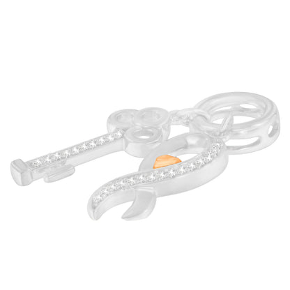 Close-up angled view of a yellow and white metal necklace pendant featuring a key and an awareness ribbon shape adorned with white round gemstones in prong settings.
