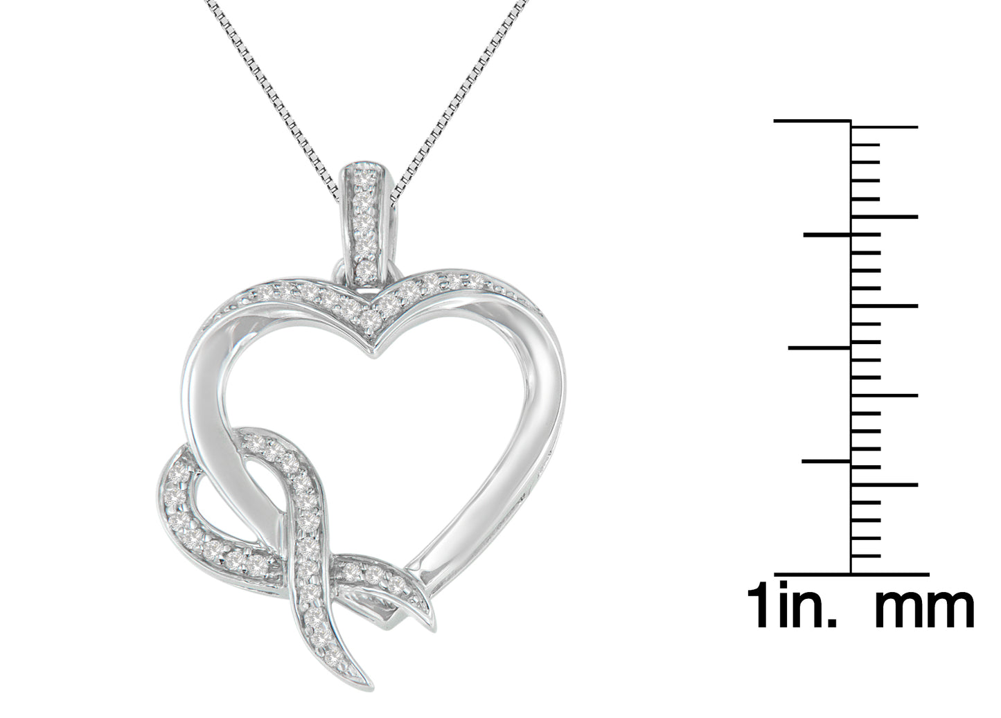 Front-facing shot of a white metal heart-shaped necklace pendant with prong-set round white gemstones, next to a ruler for size reference.
