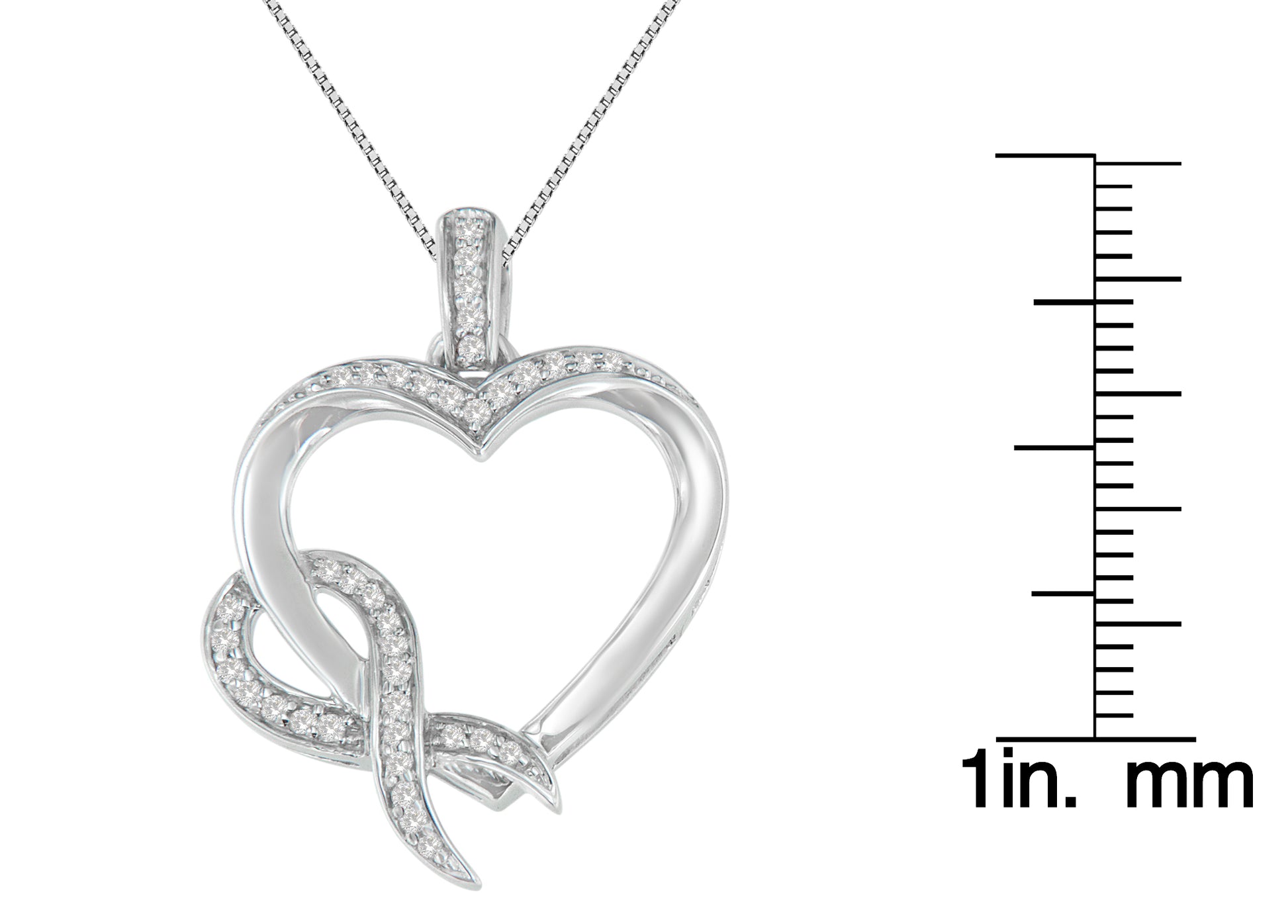 Front-facing shot of a white metal heart-shaped necklace pendant with prong-set round white gemstones, next to a ruler for size reference.