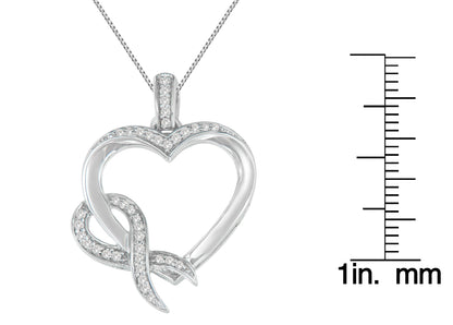 Front-facing shot of a white metal heart-shaped necklace pendant with prong-set round white gemstones, next to a ruler for size reference.