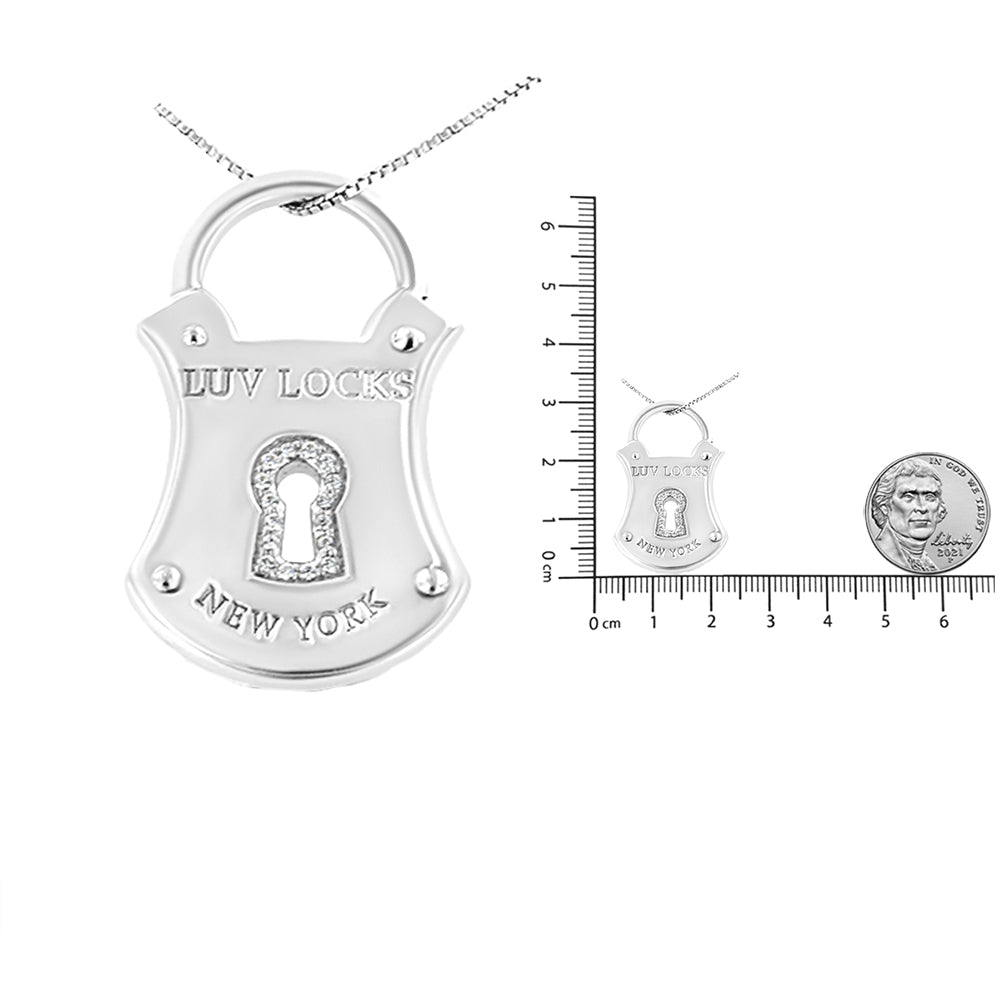Front-facing white metal necklace pendant shaped like a lock with 'LUV LOCKS NEW YORK' engraved and a keyhole set with white gemstones, shown with a ruler and coin for scale.