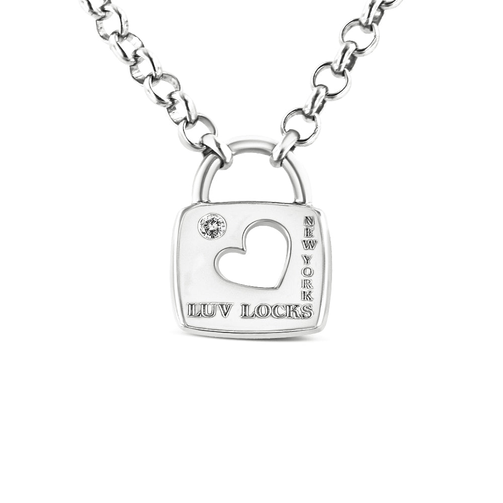 Close-up front view of a white metal necklace with a padlock-shaped pendant featuring a heart-shaped cutout, a round white gemstone in bezel setting, and engraved text 'LUV LOCKS' and 'NEW YORK'.