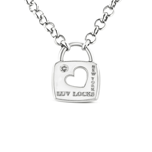 Close-up front view of a white metal necklace with a padlock-shaped pendant featuring a heart-shaped cutout, a round white gemstone in bezel setting, and engraved text 'LUV LOCKS' and 'NEW YORK'.