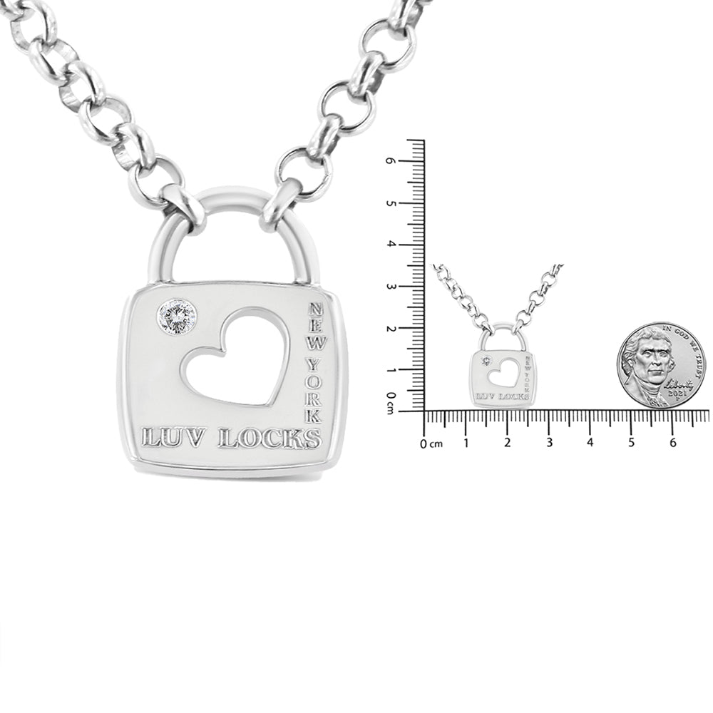 Front angle of a white metal necklace with a pendant shaped like a padlock featuring a cutout heart, a round white gemstone in bezel setting, and engraved text reading 'LUV LOCKS' and 'NEW YORK,' shown with a ruler and coin for size reference.