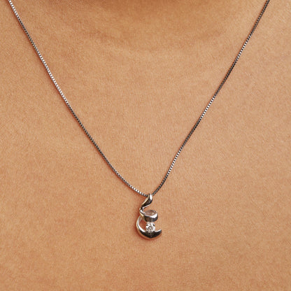 Close-up front view of a white necklace on a model featuring a pendant with a round white gemstone in a 4-prong setting.